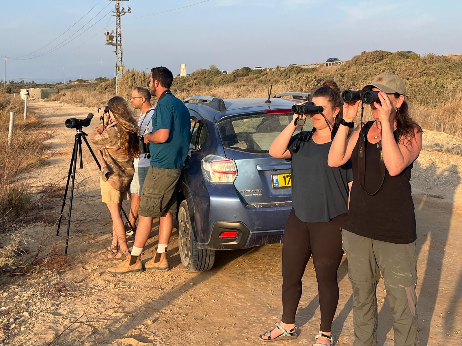 משפחה בהדרכת צפרות פרטית בשטח עם משקפות וטלסקופ