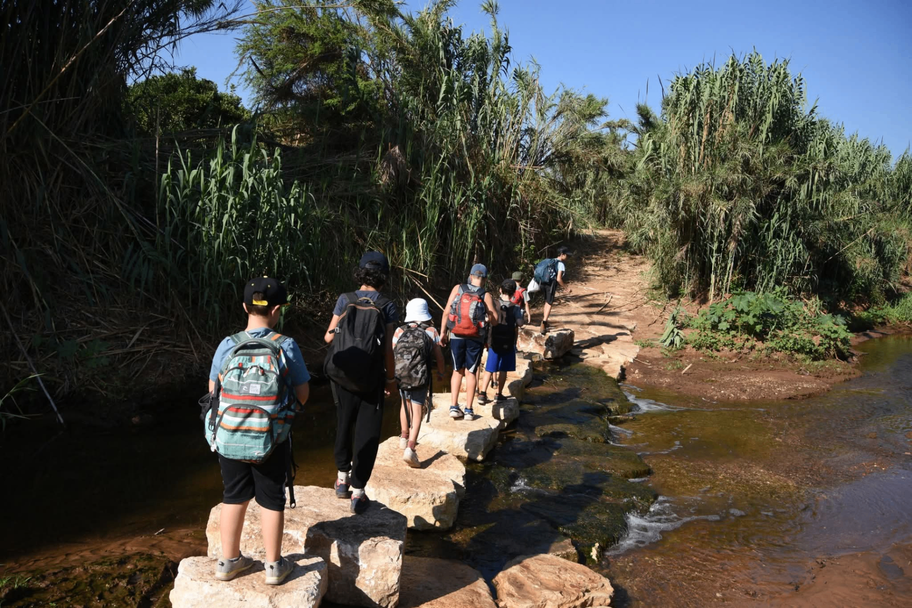 ילדים חוצים נחל בטיול חוג הטבע